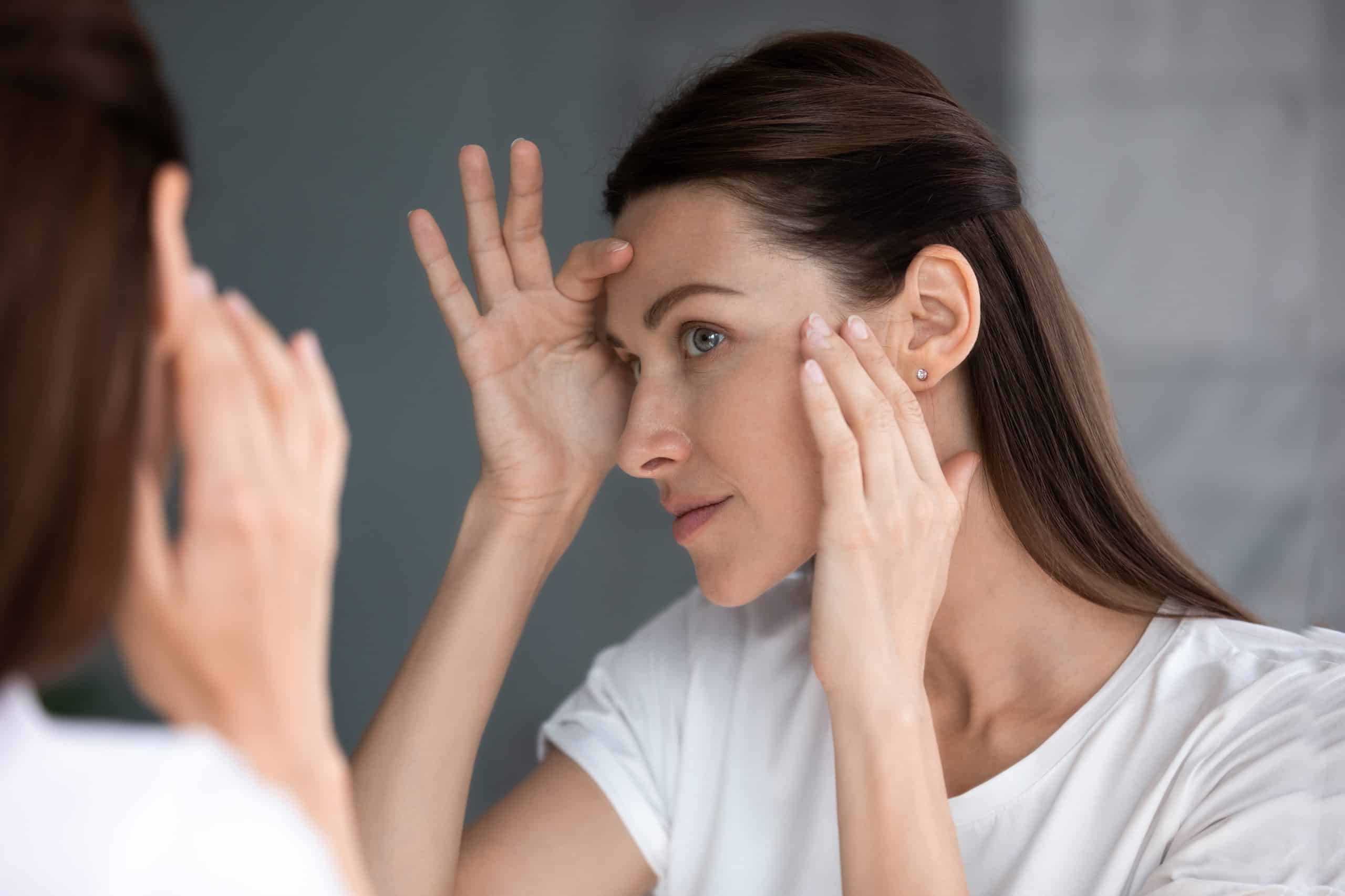 Satisfied woman looking in mirror check face after beauty treatment